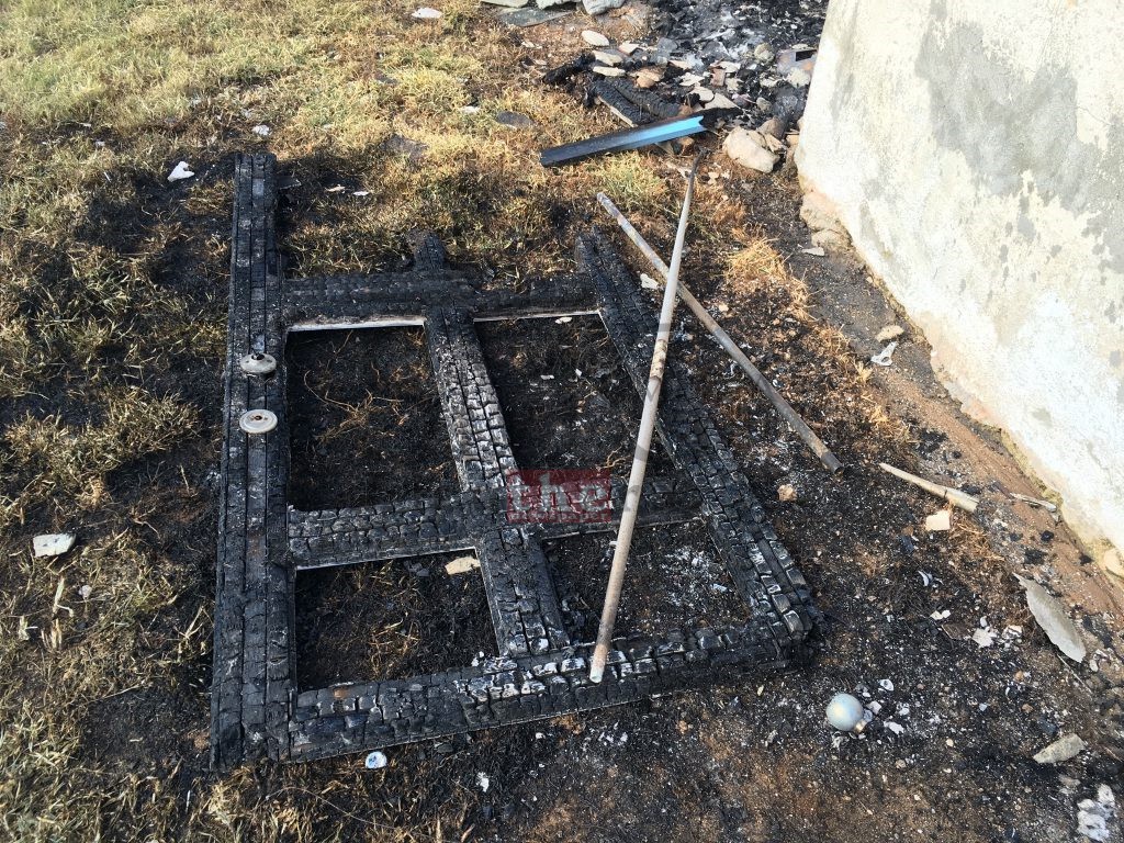 Completely burnt door structure in front of the destroyed home.