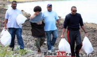 Royal Bahamas Police Force in Eleuthera, escorts the suspect and bags of items from his hiding spot.