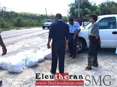 The suspect is pictured with police and bags of recovered items in Governor's Harbour, on Friday morning. 