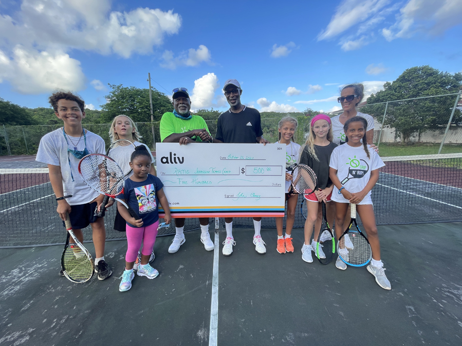 Tennis coach, Hartie Johnson with his students, accepts a donation from ALIV CEO John Gomez.