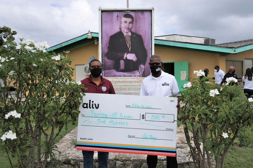 Preston Albury High School principal Tracey Mckenzie accepts a donation from ALIV CEO John Gomez.