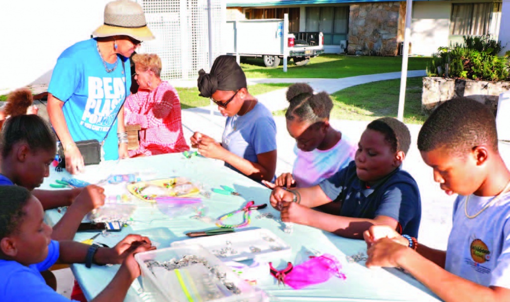 A group of children out to enjoy the Fest also have fun creating jewelry with Ms. Susan Culmer, Finance Manager with OEF and experienced jewelry artisan.