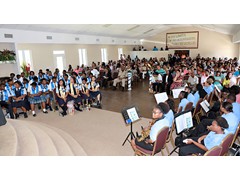 Expansive room of supportive family and friends with the school band at the front right and graduates on the left - 490A7612