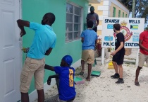Boys from the Samuel Guy Pinder All Age School assisting with the painting of the exterior of the Spanish Wells Police Station.